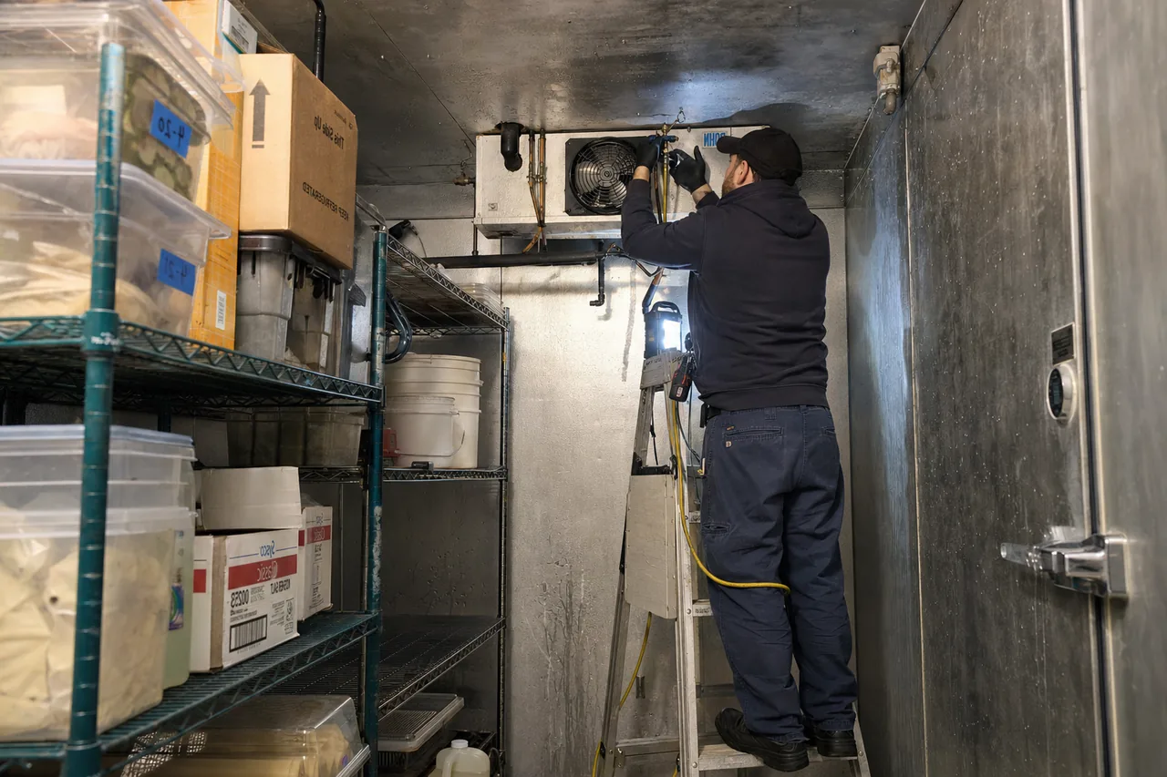 Technician servicing a walk-in cooler mid-repair